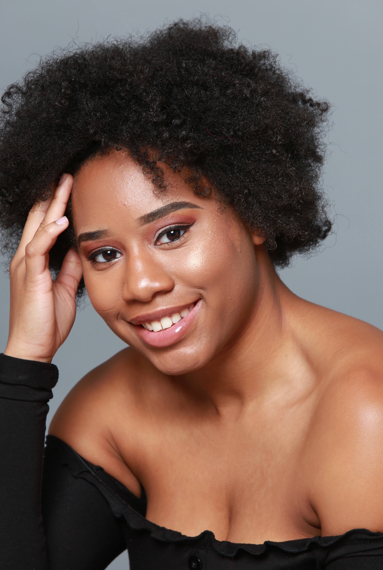 Beauty close-up of Taniya smiling with natural afro hair and glowing skin